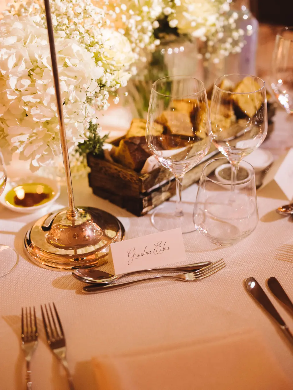 A table with glasses, cutlery and wedding flowers and a name tag