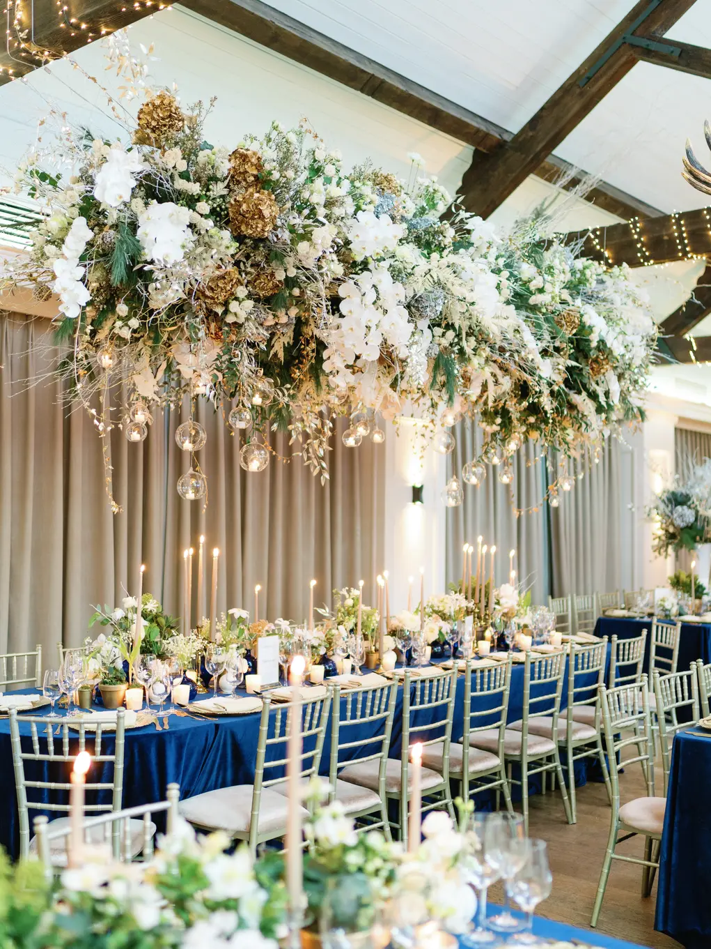 A long table decorated with white flowers and with a huge ceiling flower display