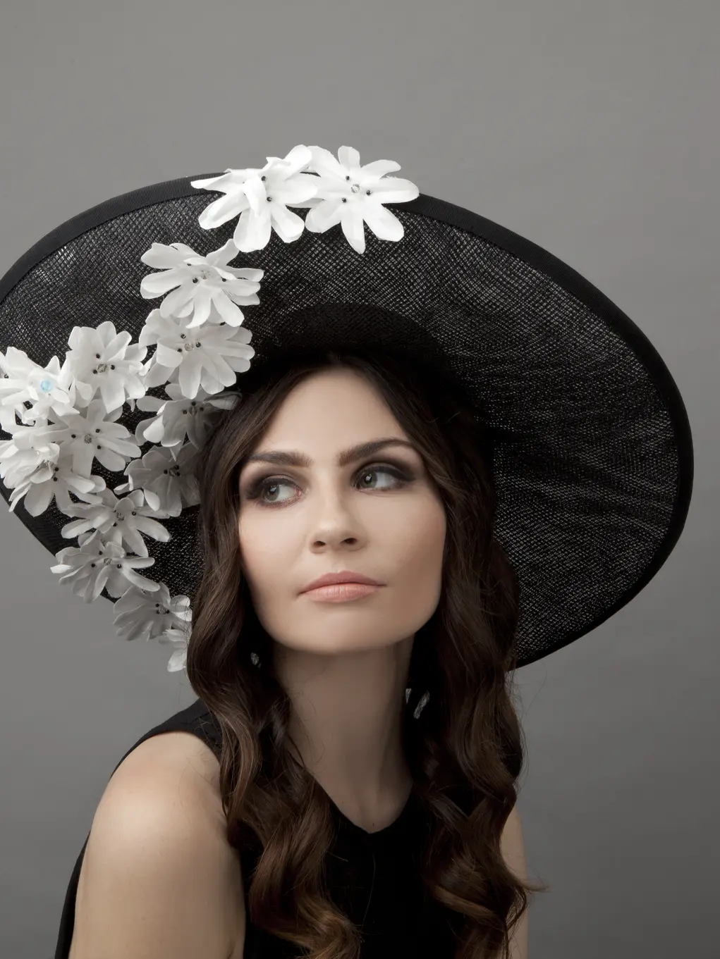 A woman in a black hat covered with white flowers