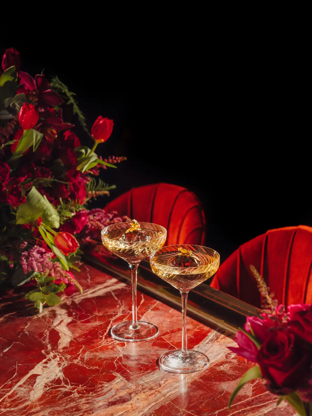 Two glasses of bubbly on a table with red roses