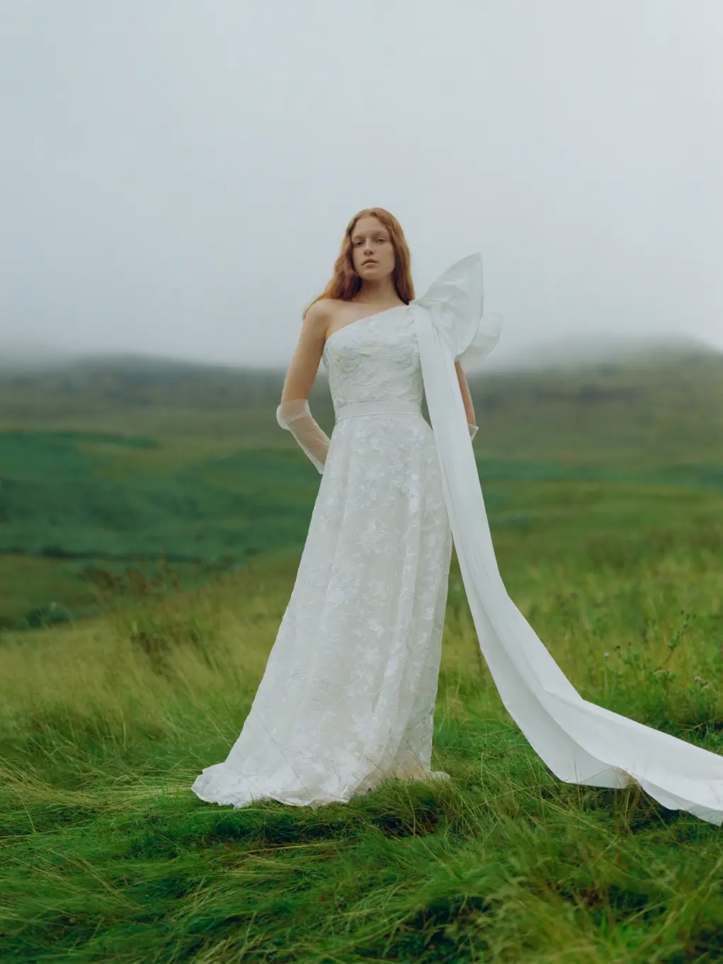 A woman wearing a white wedding dress in a grassy field