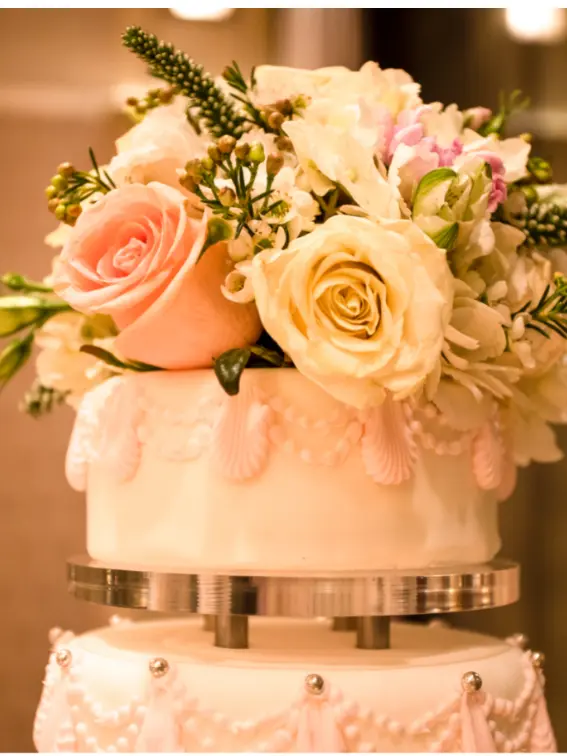 A wedding cake topped with pink and white flowers