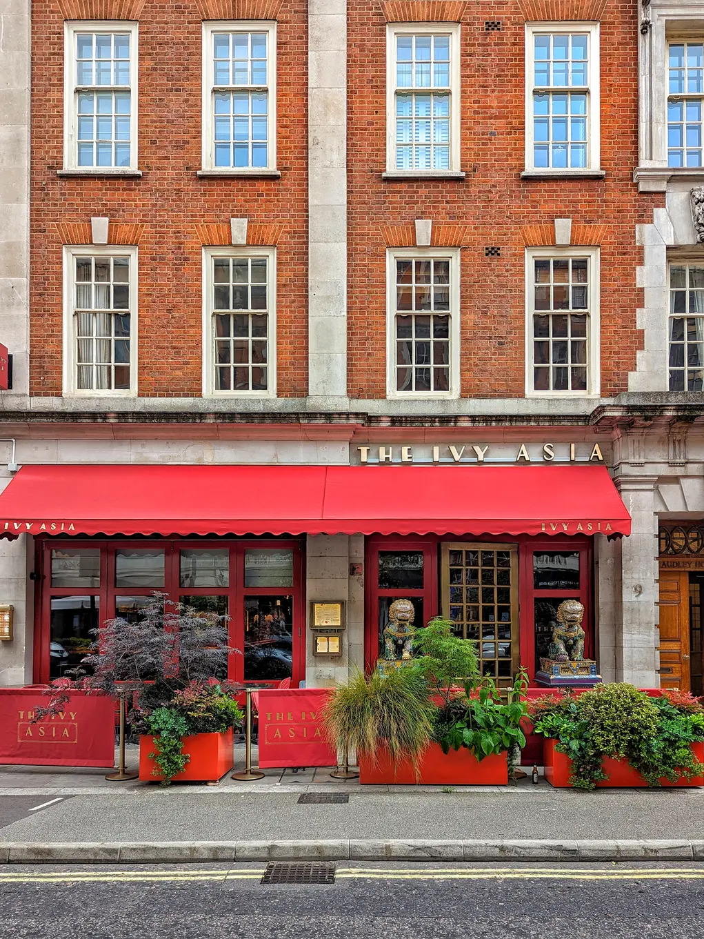 The outdoor terrace of The Ivy Asia with a red awning and planters