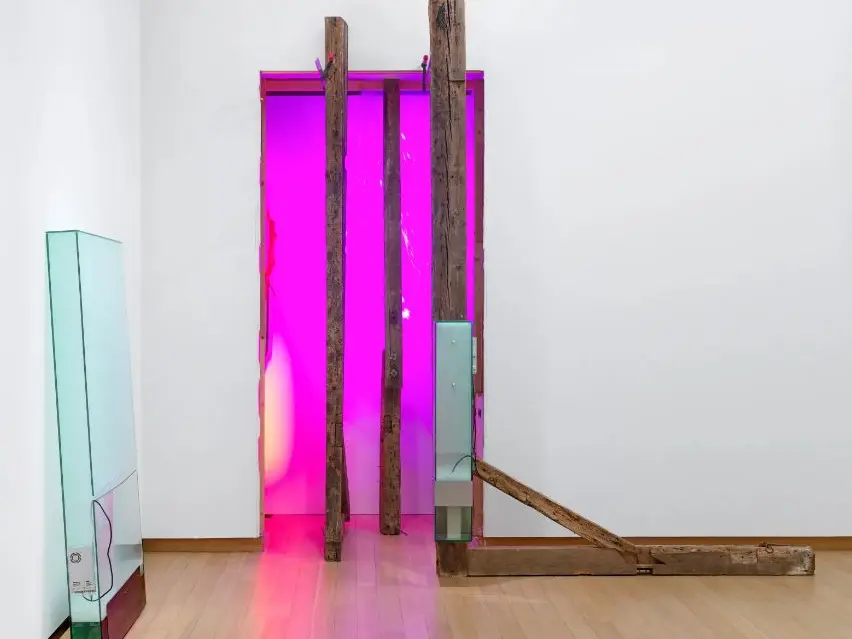 An art installation showing a rectangle of pink neon with wooden beams