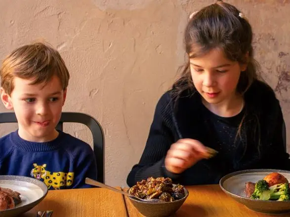 A boy and a girl eating plates of food
