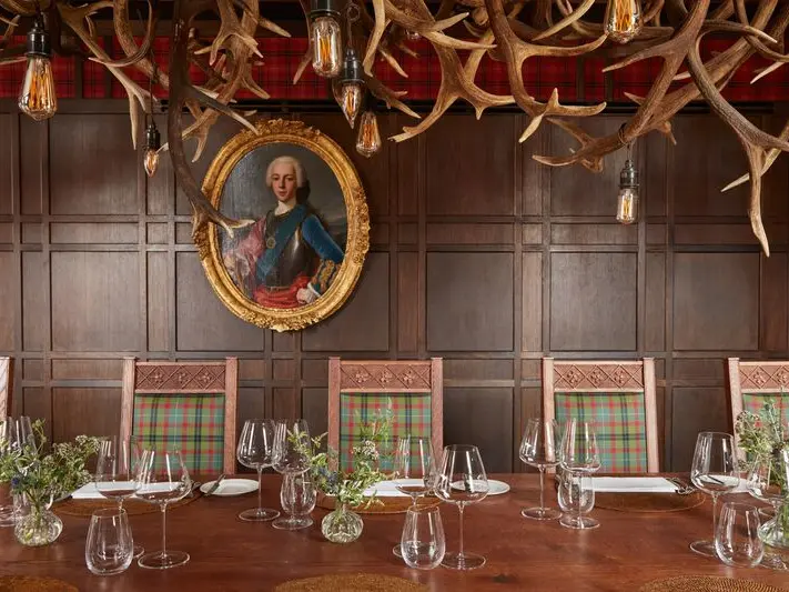 A long table with five chairs and antlers on the wall